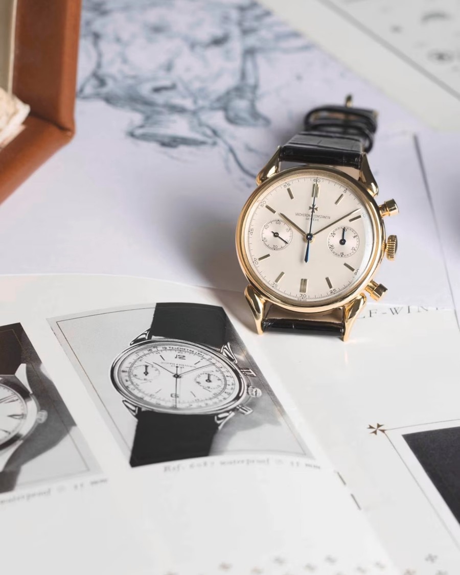 Black and white photo of a watch leaning against a watch from a picture with a leather strap, gold bezel and light case