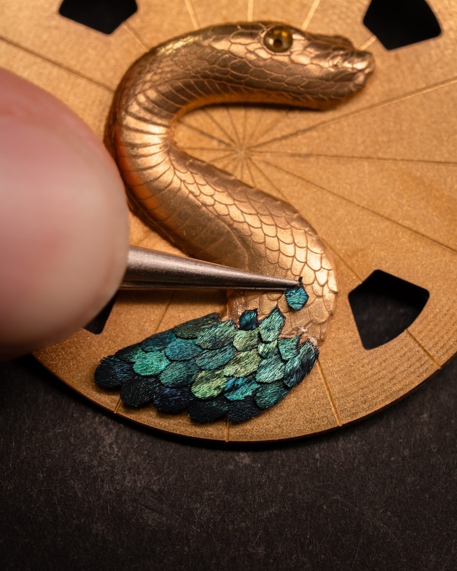 Tweezers positioning feathers on the featherwork concept watch.