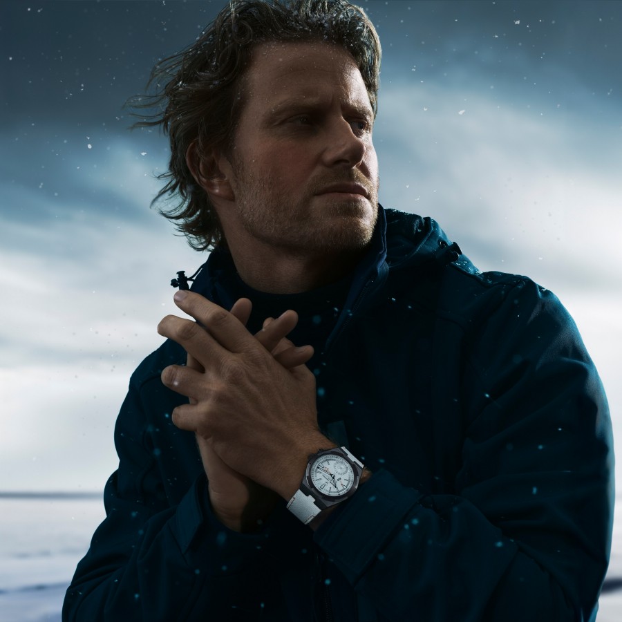 Cory Richards portant la montre Overseas Dual Time Cardinal Points blanche avec un fond enneigé.