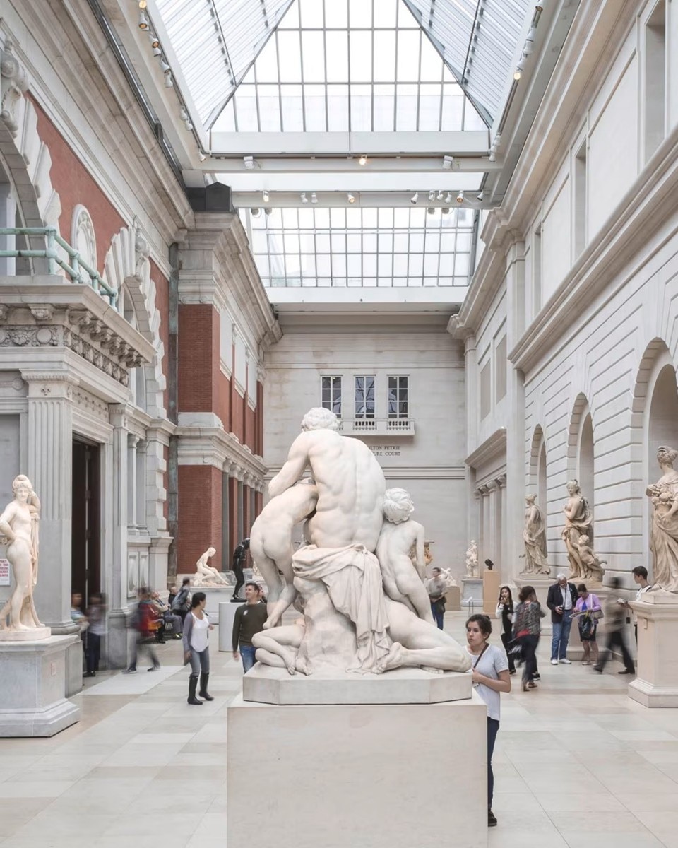 Interior view of a museum gallery with large sculptures and visitors.