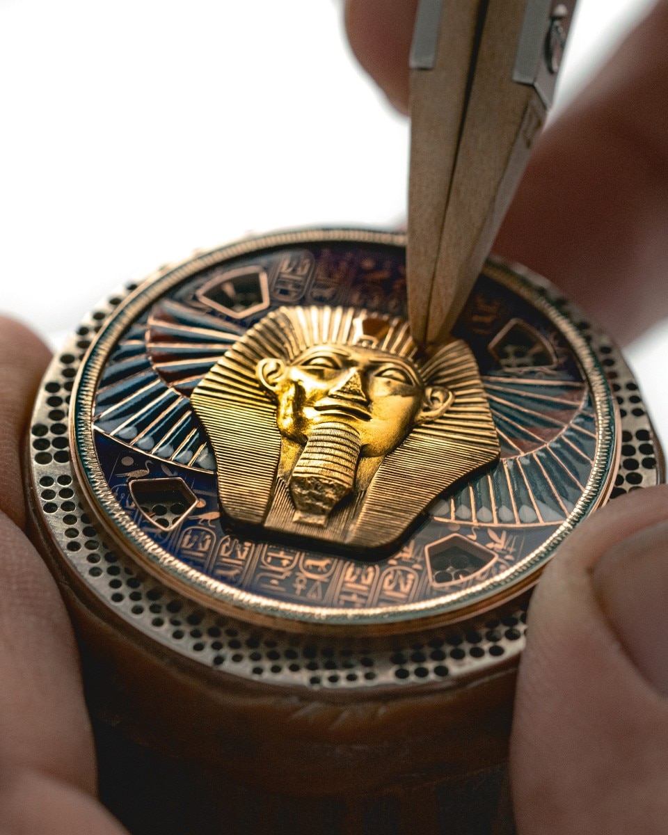 Watch dial with a pharaoh's head being sculpted in gold.