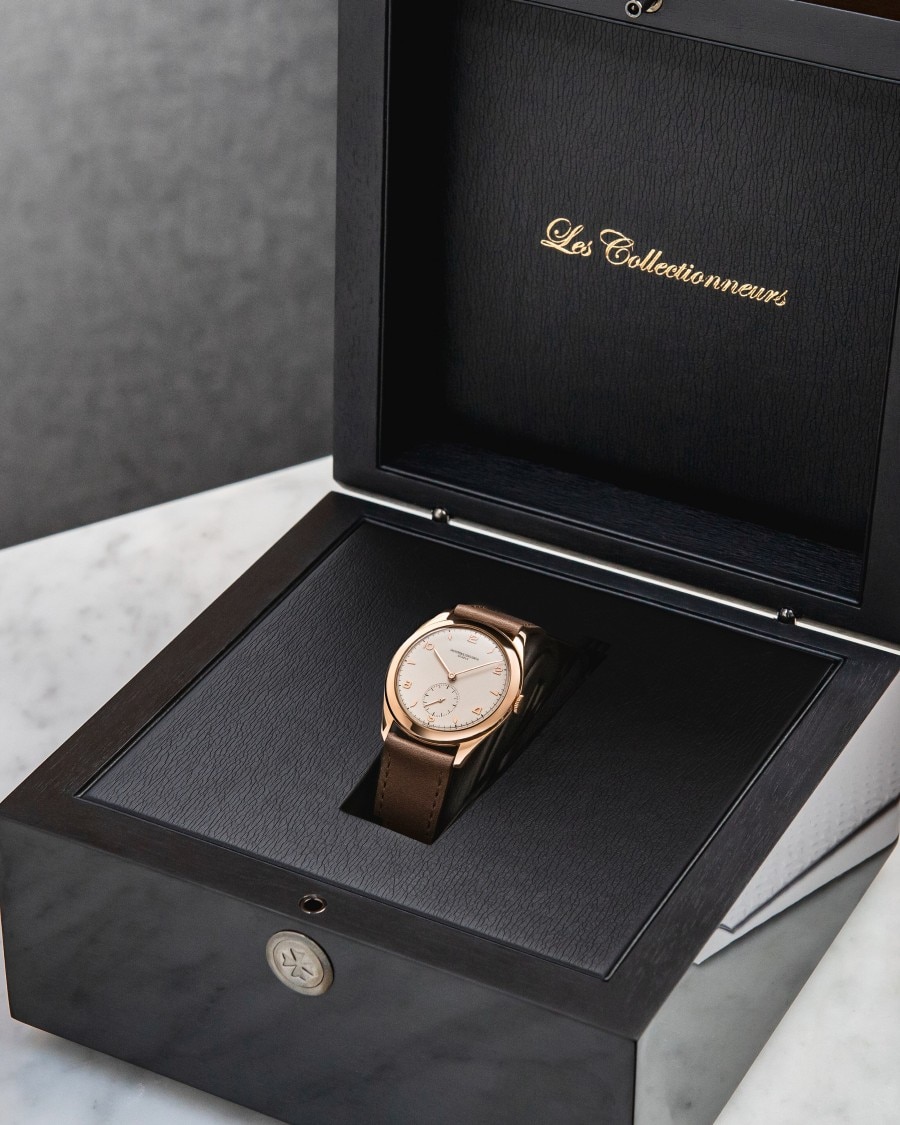 Luxury wristwatch with a brown leather strap displayed in an open black presentation box labeled "Les Collectionneurs".