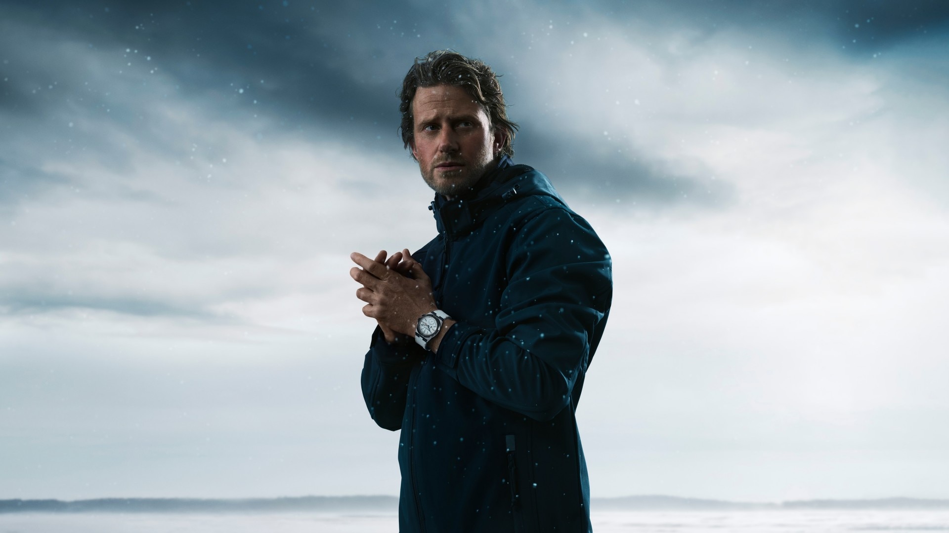 科里·理查茲佩戴白色Overseas兩地時“基本點”腕錶，背景為雪景。