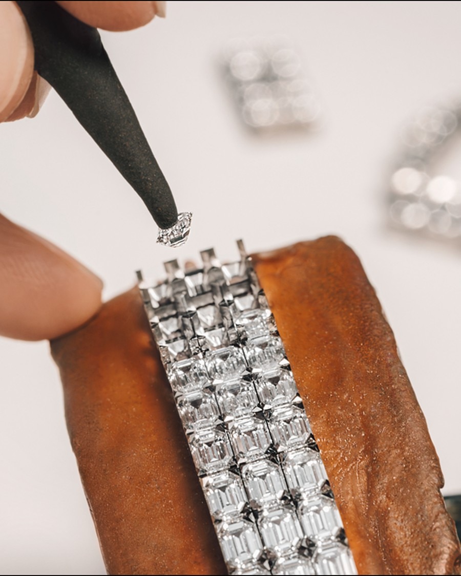 Placing a diamond into the setting of a braclet composed of rectangular and square-cut stones.