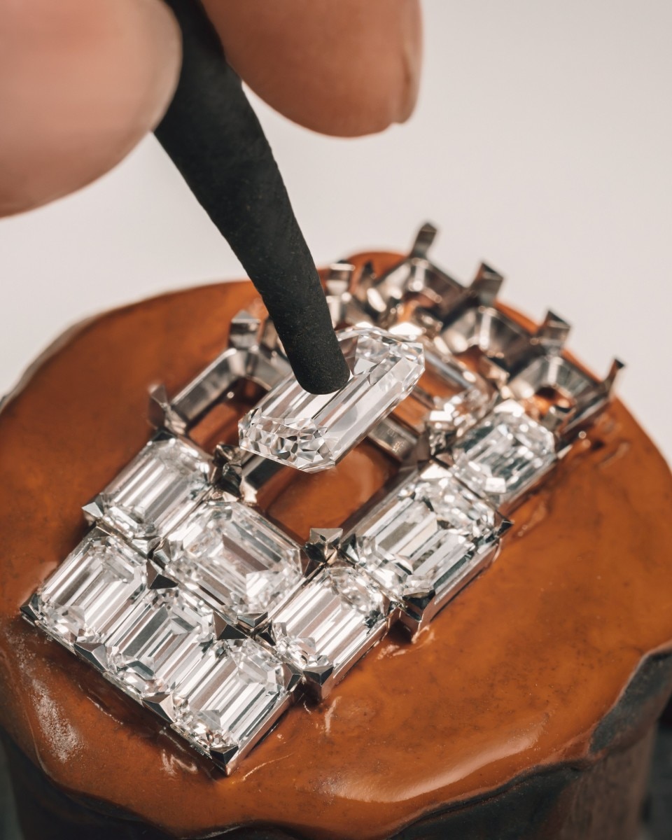 Placing a large rectangular diamond into a geometric setting with multiple emerald-cut stones.