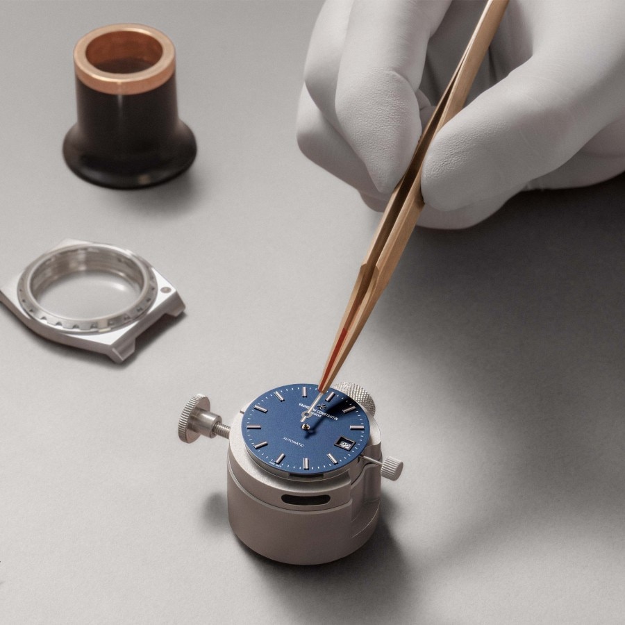 Watchmaker working on the blue dial of the Historiques 222 in steel