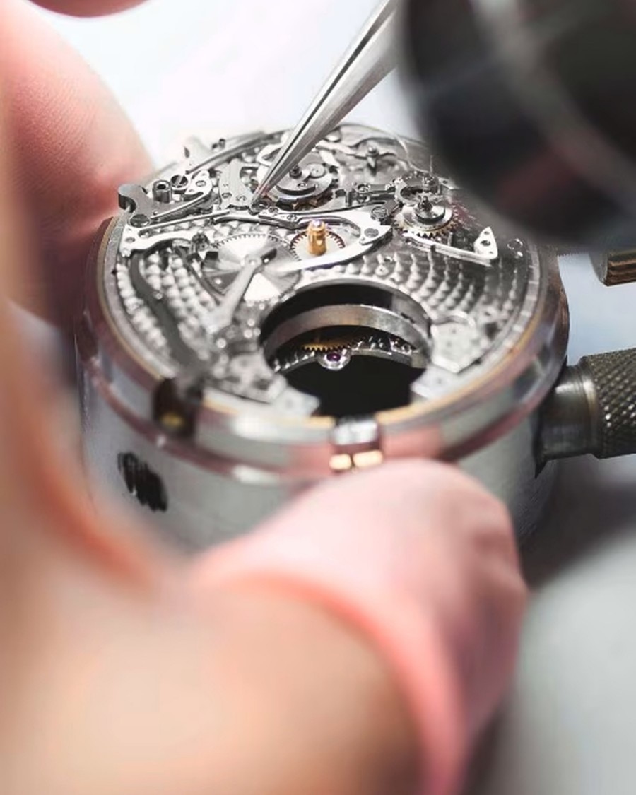 Мастерство Close-up of a watchmaker assembling a mechanical watch movement using precision tweezers.