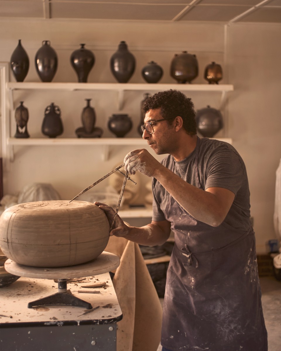 Un uomo modella un vaso in argilla nel suo atelier.