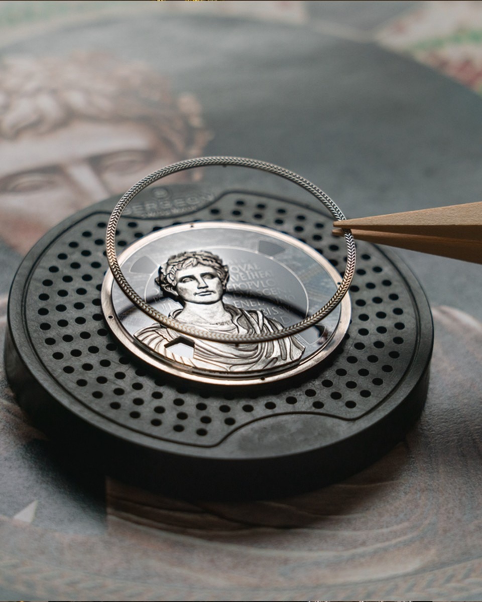 Engraved watch plate featuring sculpted classical figures placed on a drawing.