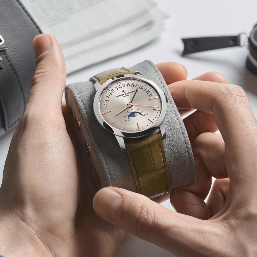 Two hands unpacking Vacheron Constantin watch with leather strap and silver bezel and details