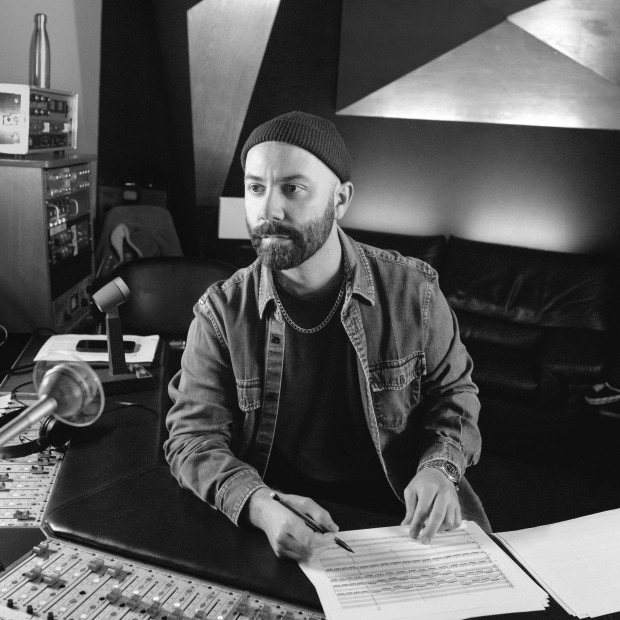 Woodkid in a studio, reviewing sheet music.