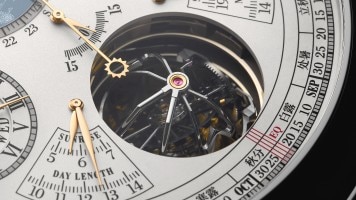 Primo piano di un quadrante di un orologio con scale del calendario e tourbillon a vista.