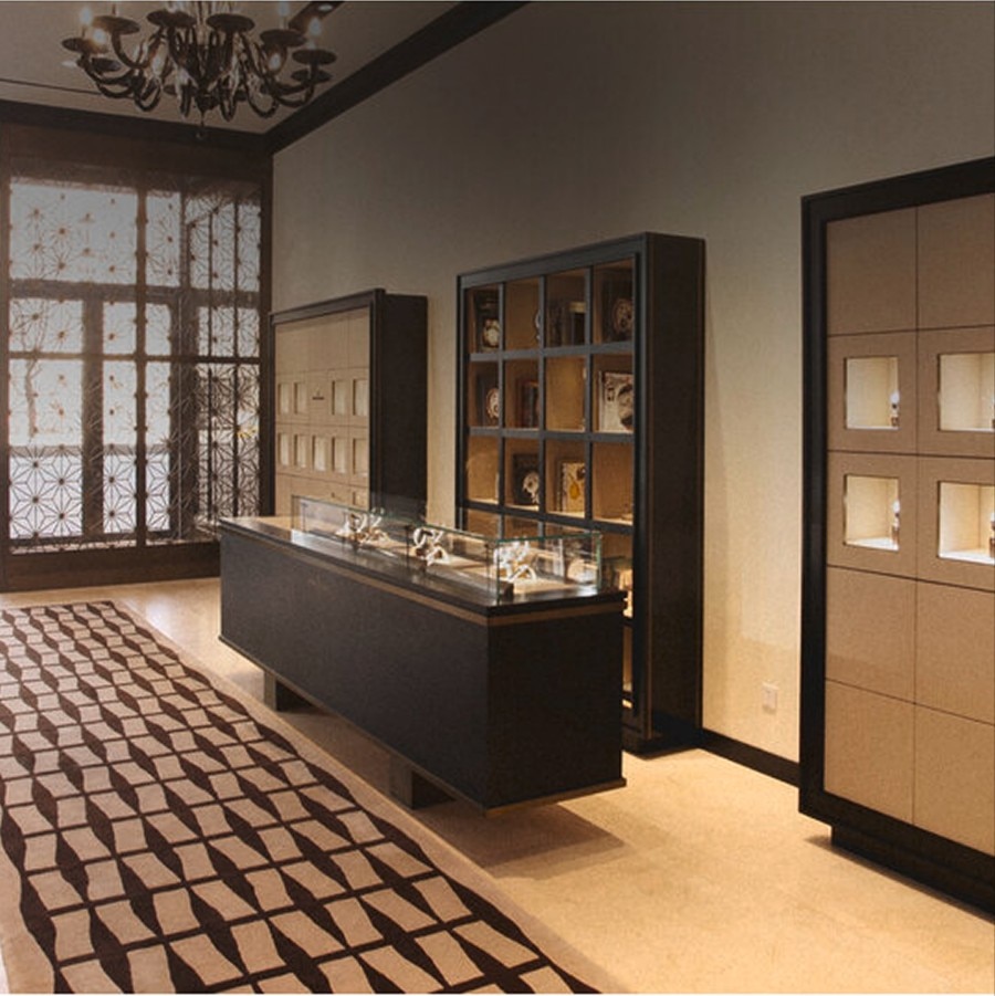 Interior of a luxury watch boutique with display counters, illuminated shelves, and large windows.