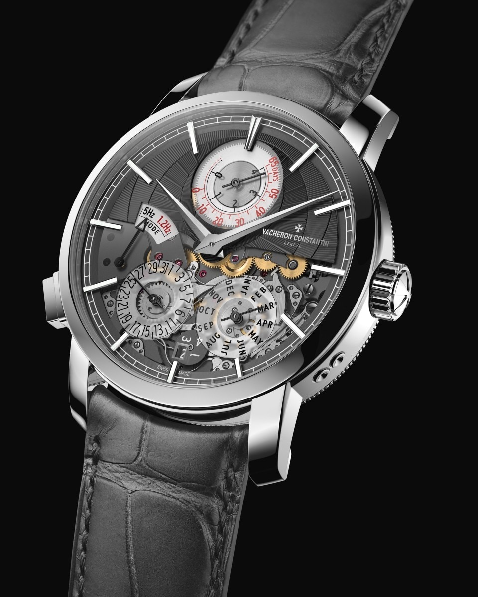 Close-up of a luxury watch with a dark grey dial, exposed mechanics, and a dark leather strap.