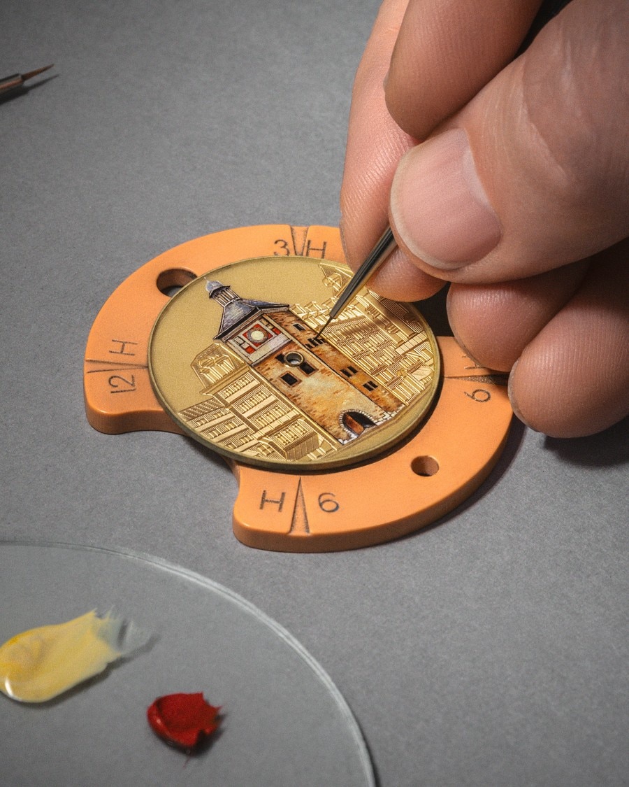 Close-up of a hand  engraving fine details into a watch dial with a precision tool.