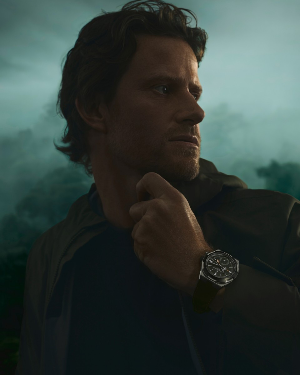 Кори Ричардс с зелеными часами Overseas Dual Time Cardinal Points на лесном фоне