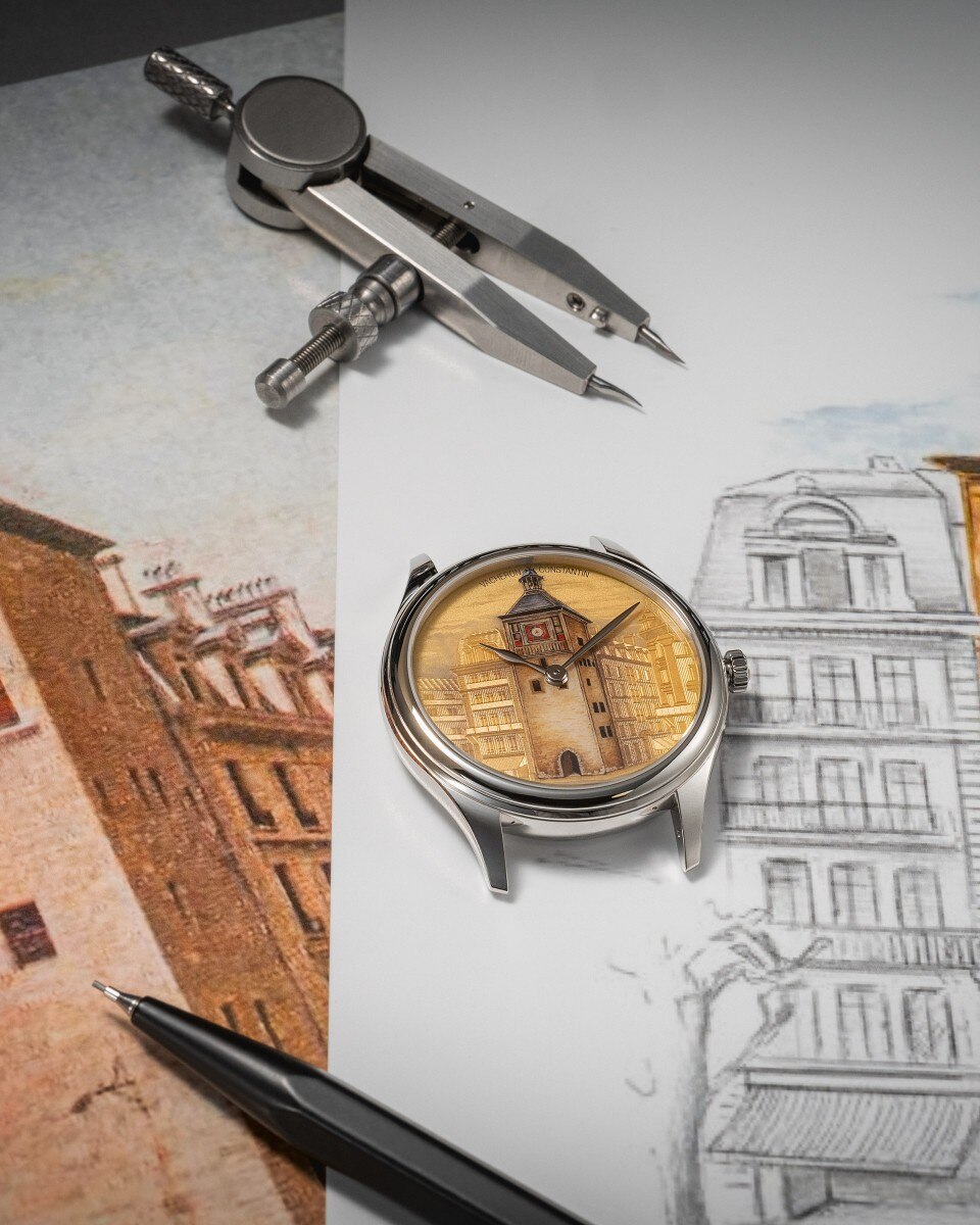 Orologio con quadrante dipinto raffigurante una torre cittadina appoggiato su schizzi architettonici e strumenti da disegno.