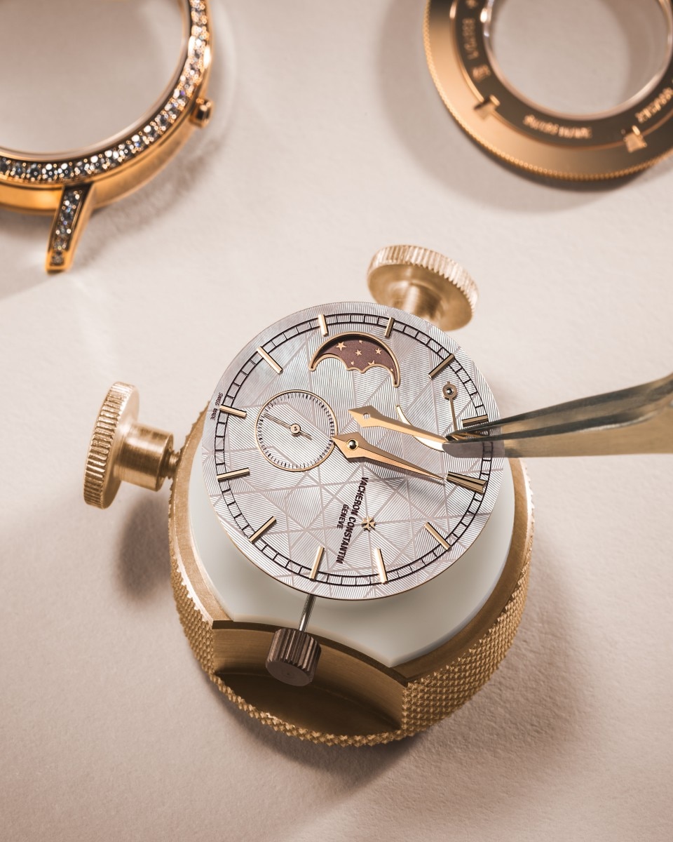 Watchmaker setting the hands on a moonphase watch dial.
