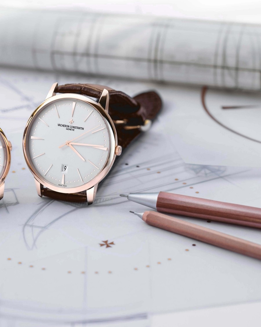 Watch laying on a drawing with pencils