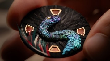 Artista al lavoro sul concept-watch con decorazioni in piume.