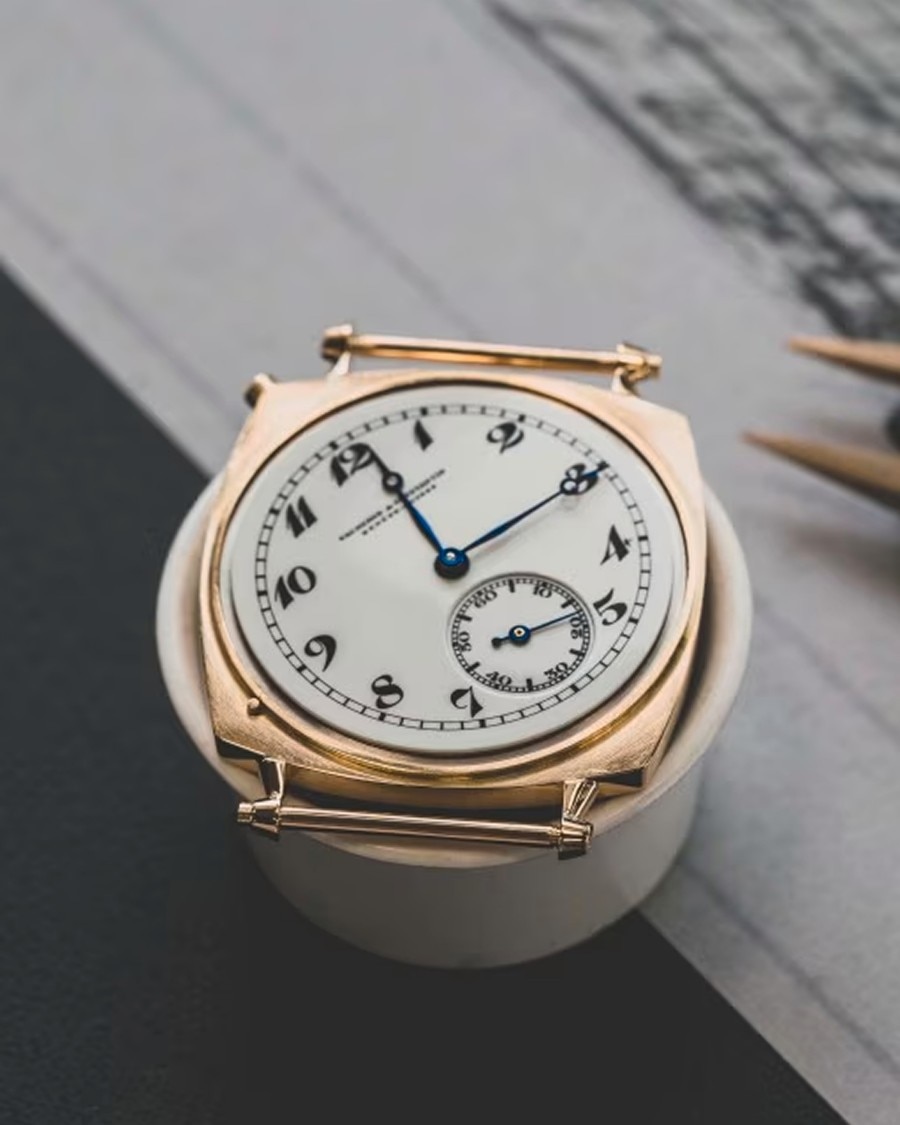 Longevità Top view of a vintage-style Vacheron Constantin watch with a white dial, black numerals, and small seconds subdial, placed on a dark surface.