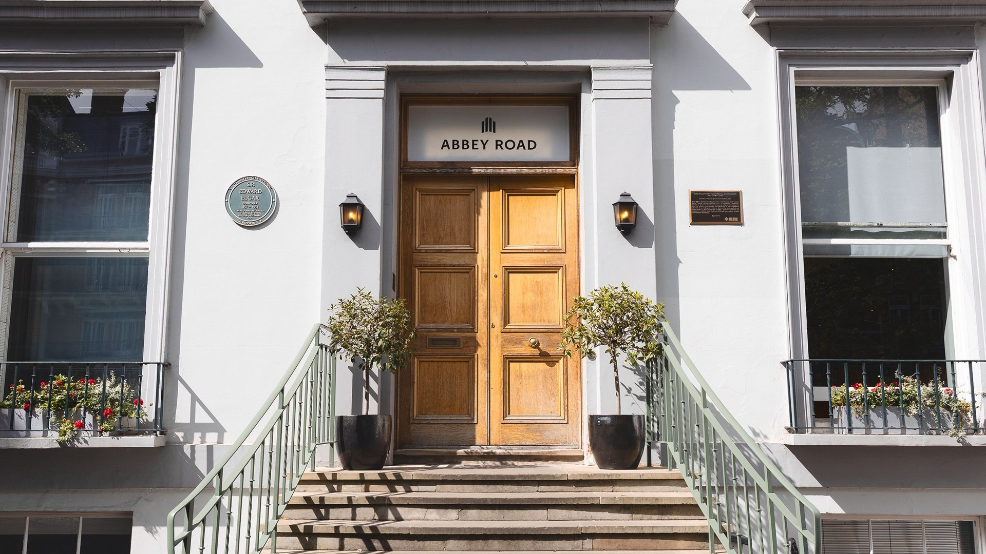 Front entrance of Abbey Road studios with wooden doors and two potted plants.