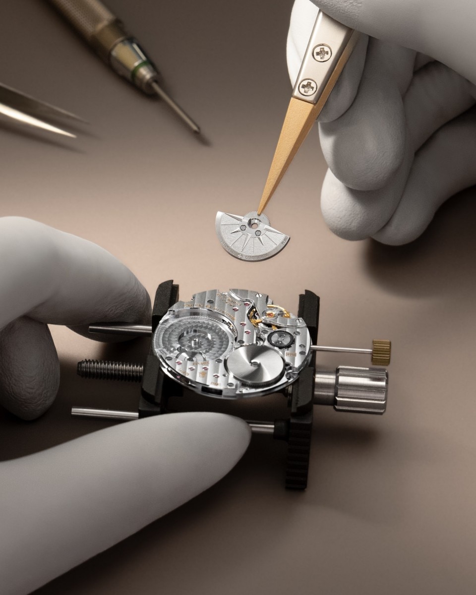 Watchmaker assembling a mechanical watch movement using precision tweezers and tools.