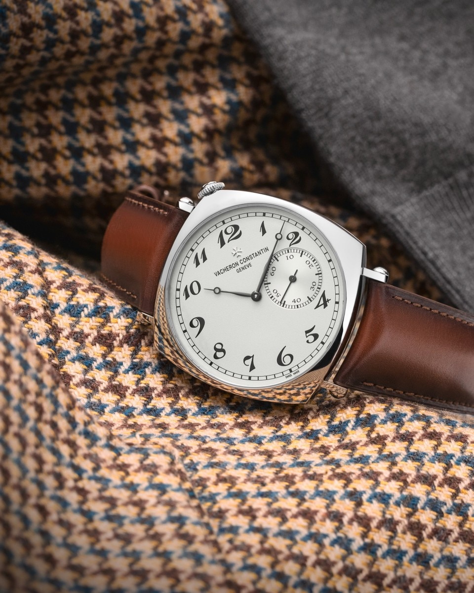 A watch with a light-colored dial, a gold case, and brown leather straps.