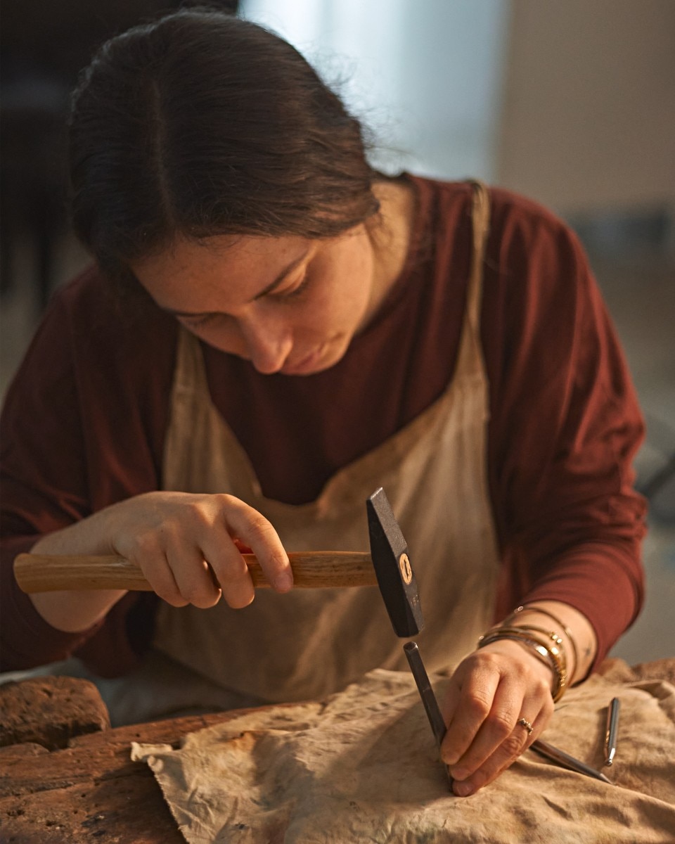 Una donna intaglia un pezzo di legno nel suo atelier.