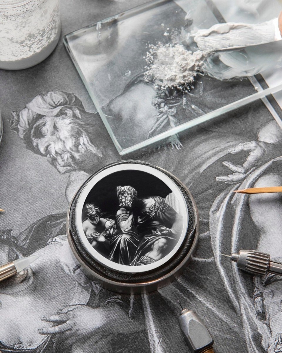 Black-and-white close-up of a watch dial featuring a Roman figure, placed on a drawing with fine engravings.