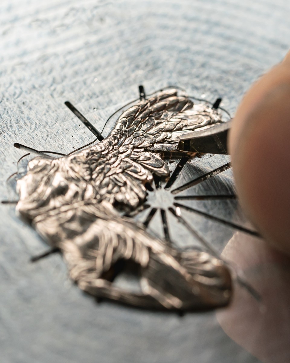 Detailed engraving of a winged figure on a flat metal surface.