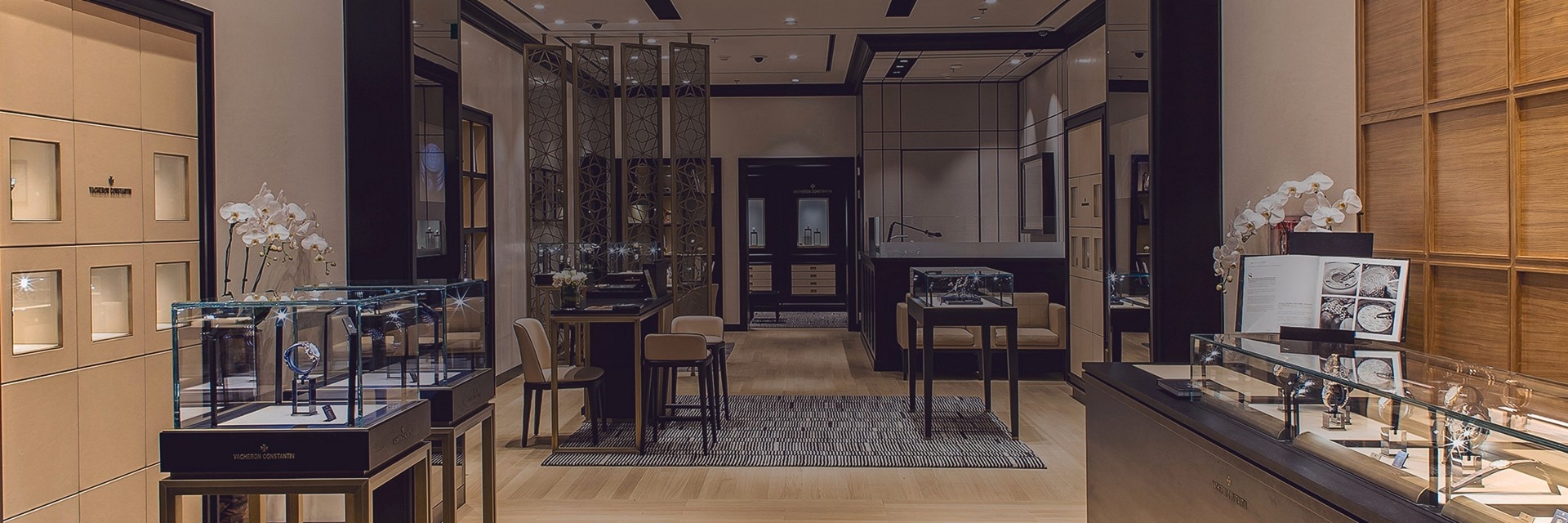 Vue intérieure d’une boutique Vacheron Constantin avec des comptoirs élégants et des vitrines de montres illuminées.