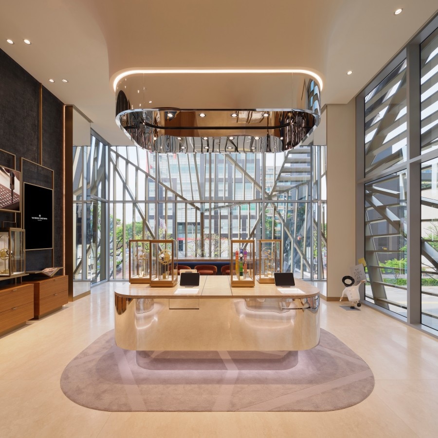 Inside the Vacheron Constantin boutique in Seoul. It features a central island in soft gold tones and large windows filled with natural light.