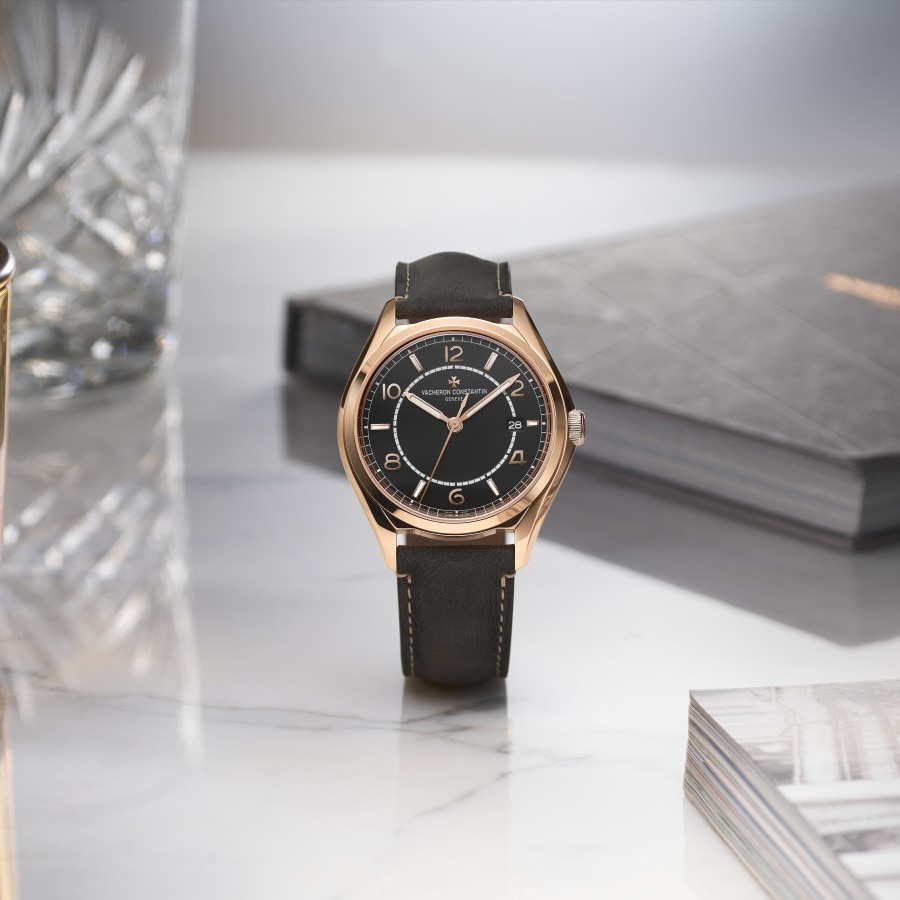 Black dial Fiftysix with a black strap, books and a glass around