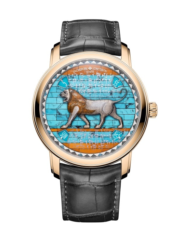 A gold wirstwatch with a black leather strap, featuring a dial inspired by ancient Mesopotamian art, depicting a lion against a blue and orange background with cuneiform script.