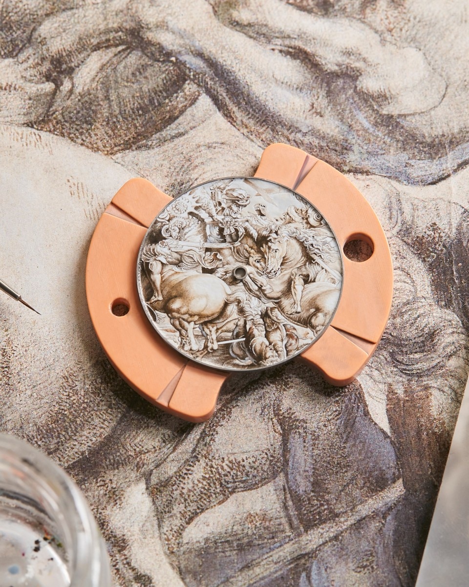 Engraved watch plate featuring sculpted classical figures placed on a drawing.