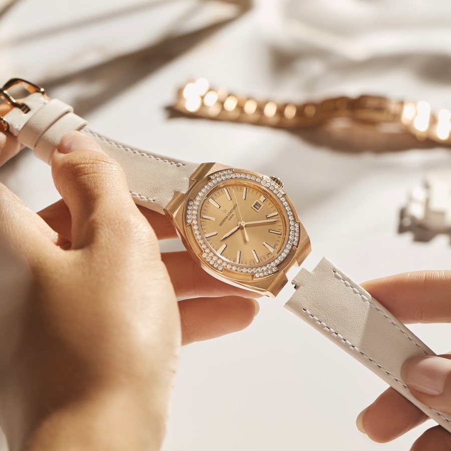 Women adjuting the interchangeable white strap of an Overseas Self-winding in pink gold with a bezel set with diamonds