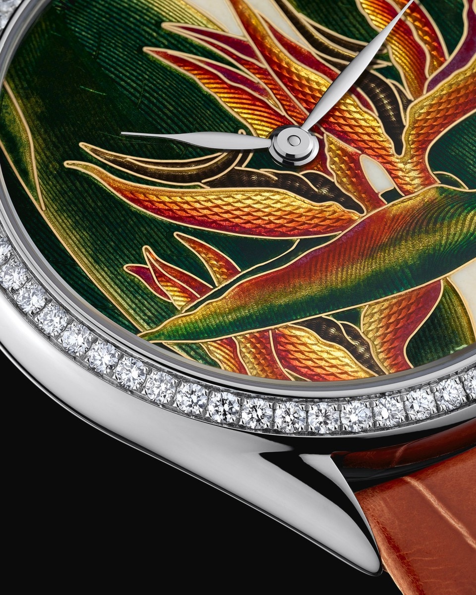 Close-up of a finished watch with a tropical bird enamel dial and diamond-set bezel.