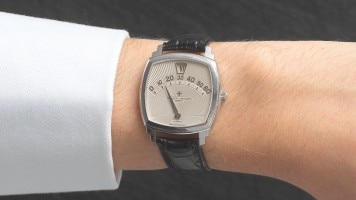 A woman's wrist wearing a watch with a black leather strap and a silver face.