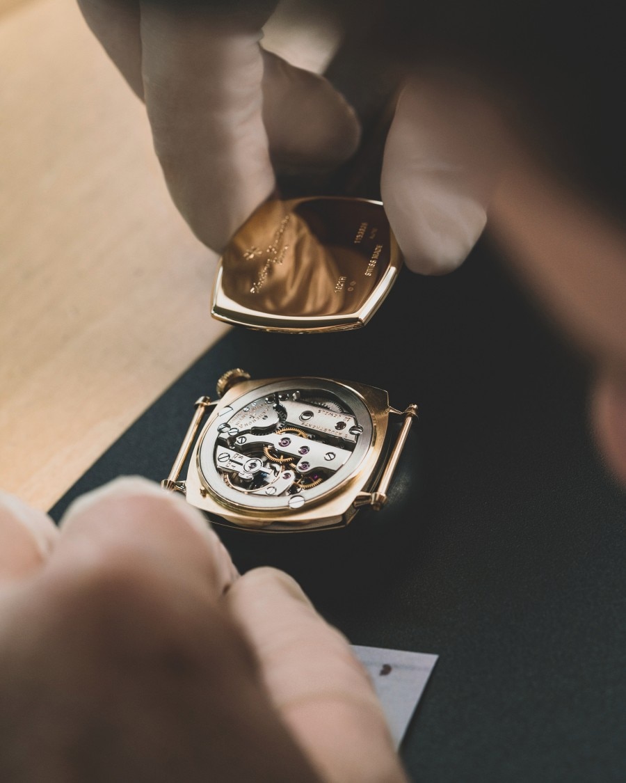 Hands are assembling the golden watch case