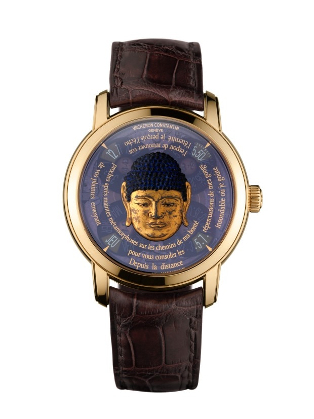A golden wirstwatch with a blue dial featuring a golden Buddha face and Franch text, paired with a brown leather strap.