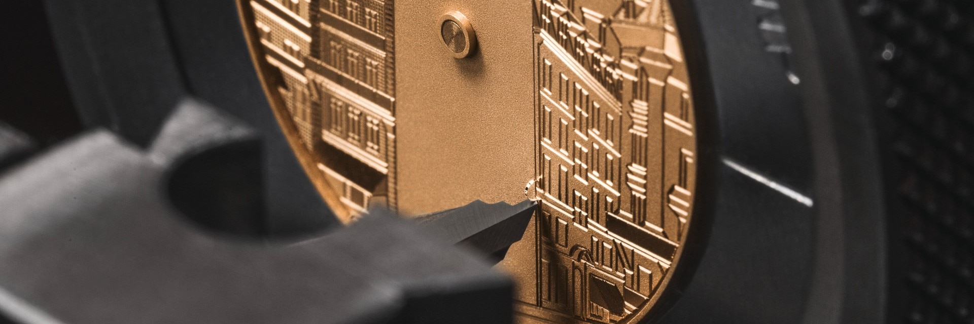 Close-up of an engraved watch dial with architectural details, viewed through magnification.