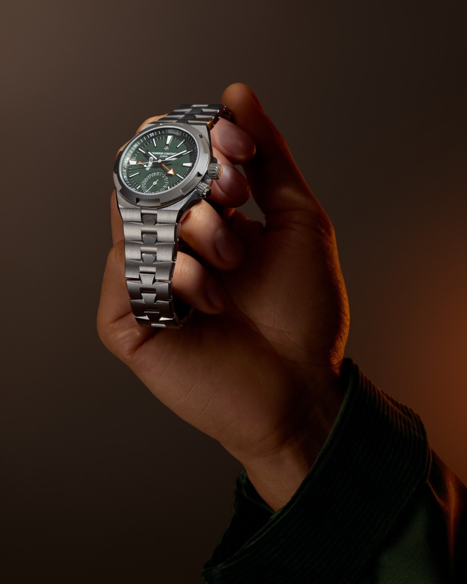 Una mano regge un orologio Vacheron Constantin Overseas Dual Time Punti Cardinali con bracciale in metallo.