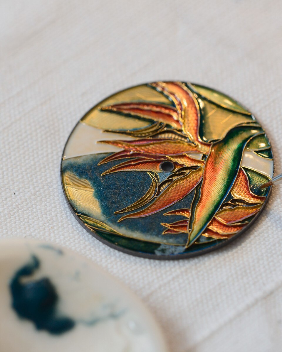 Standalone enamel dial featuring a vibrant bird of paradise motif in red, green, and gold.