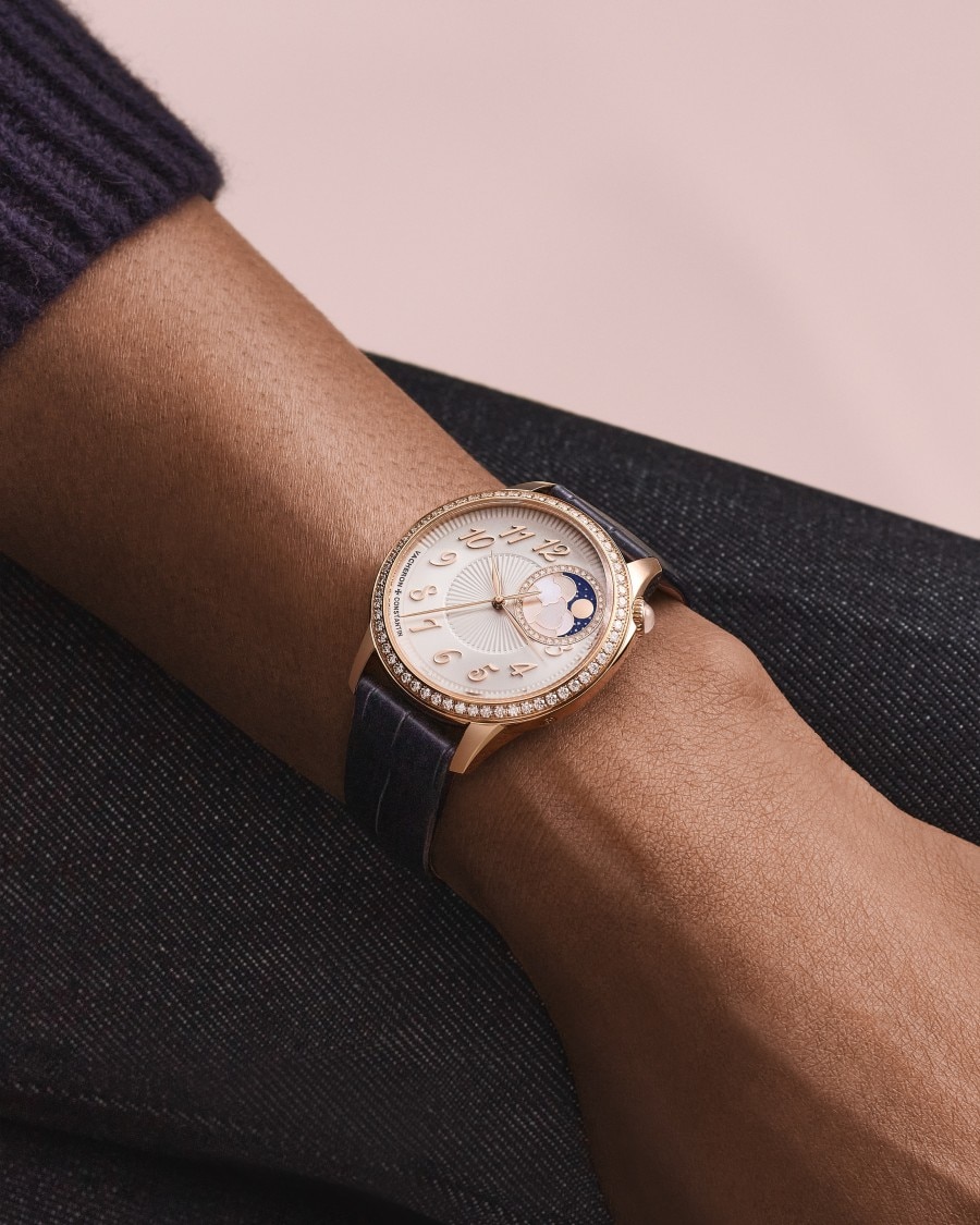 Egérie  Égérie watch with white dial and gold case on wrist in dark sleeve.