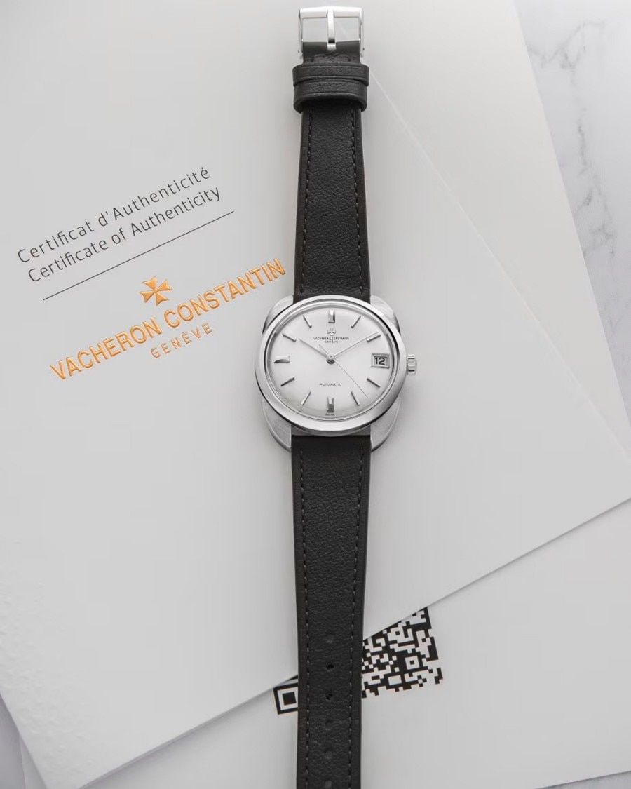 Close-up of a watch with a black leather strap, white case, and silver bezel and details