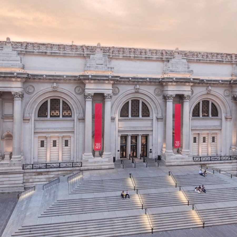 Vista esterna del Met Museum con ampi gradini e striscioni rossi.