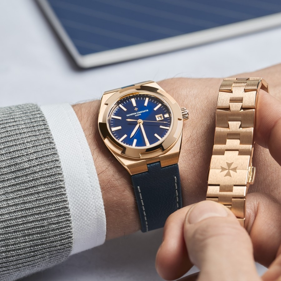 Man wearing an Overseas Self-winding in pink gold with a blue dial and a blue strap, a pink gold compatible strap in his other hand