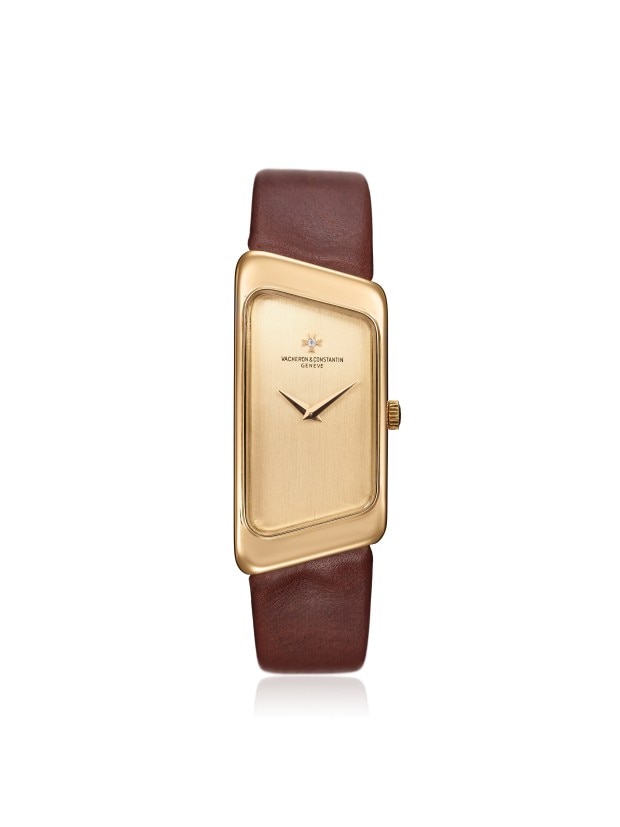 A uniquely shaped gold wirstwatch with a brown leather strap and an asymmetrical case design.