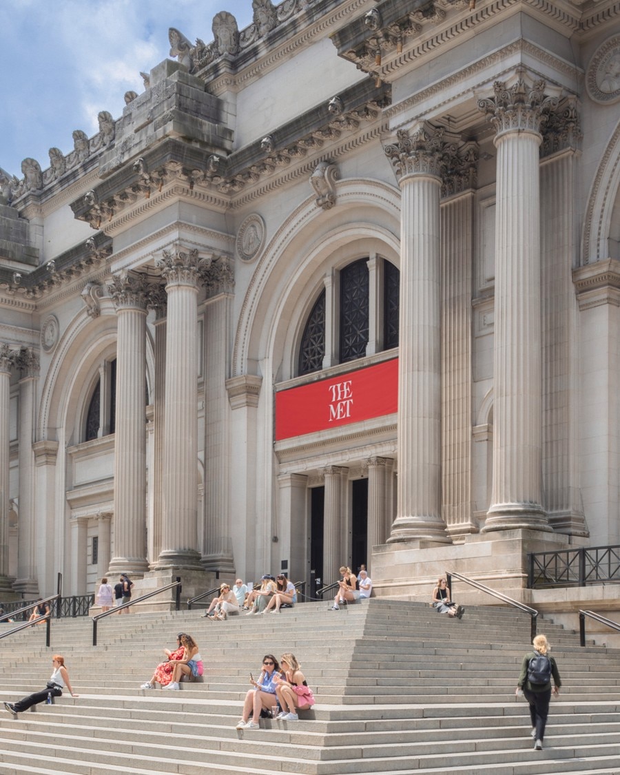 Front view of the Met museum with people seating on the stairs